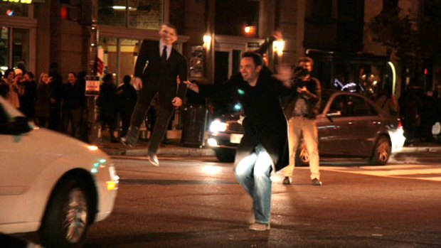 A man with an Obama cardboard cut-out stops traffic.