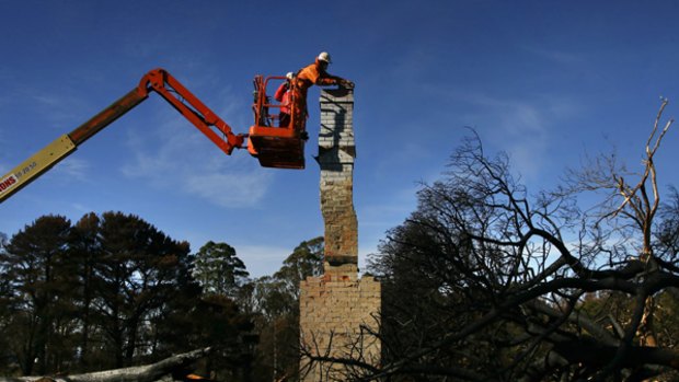 Bricklayer George Firczak begins dismantling a chimney left after the Black Saturday fires swept through Kinglake. It will become a memorial.