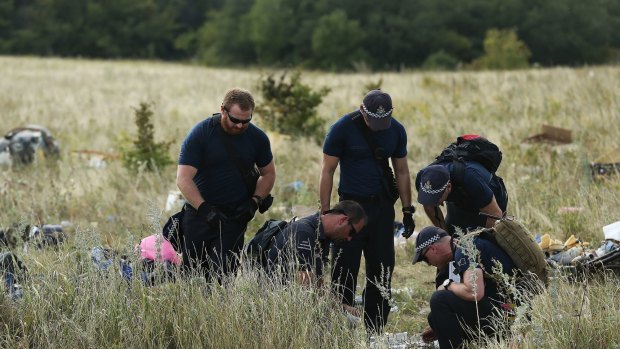 Australian Federal Police officers and their Dutch counterparts collect human remains from the MH17 crash site. 