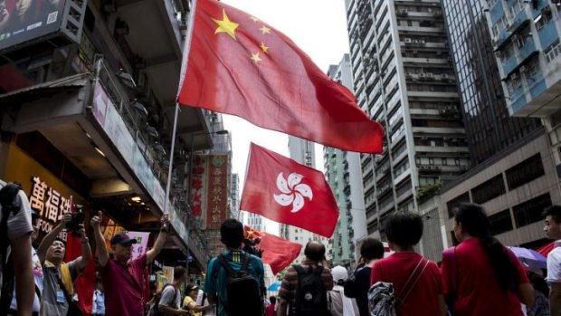 People hold the Chinese and Hong Kong flags as they take part in the demonstration.
