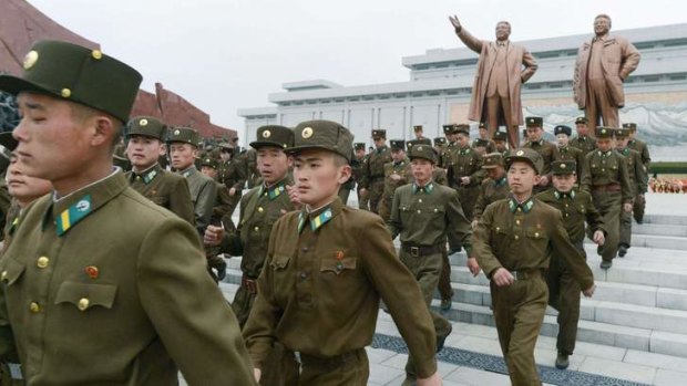 Military state: North Korean soldiers march past statues of the country's two former leaders.