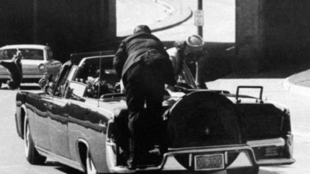 Jacqueline Kennedy leans over the slumped body of her husband, US President John F. Kennedy, moments after the fatal shots, as secret service agent Clint Hill rushes to the car.