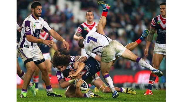 Cop that: Melbourne Storm stars Cooper Cronk and Kevin Proctor tackle Rooster Roger Tuivasa-Sheck during Saturday night's victory.