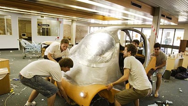 Red faces... first-year engineering students with the all-electric ManGo. The car is 155 centimetres wide, five centimetres wider than the workshop doorway.