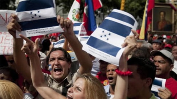 Demonstrators hold up copies of Honduras flag as they take part in a show of support for ousted President Manuel Zelaya.