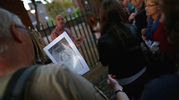 An old black and white photograph of a victim is passed around a group during a Jack the Ripper guided walk in London.