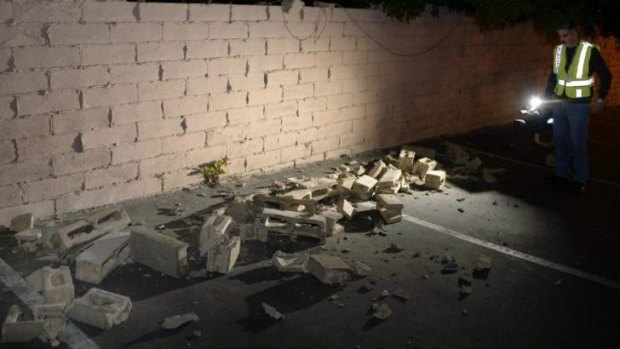 News cameraman Juan Guerra records a video of a fallen brick wall after a magnitude 5.1 earthquake in Fullerton, California.