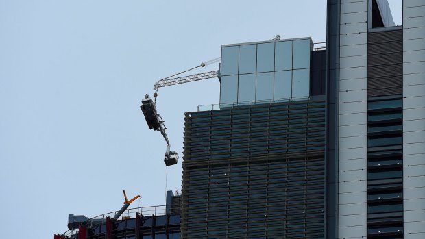 The damaged crane hangs from the 51st floor of the highest tower at Barangaroo in the Sydney CBD.