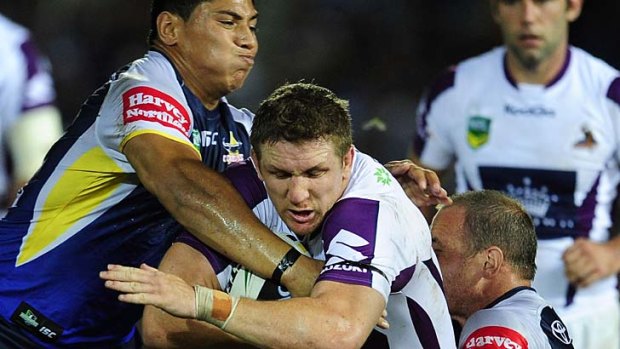 Going nowhere: Ryan Hoffman of the Storm is tackled by Jason Taumalolo and Matthew Scott of the Cowboys.