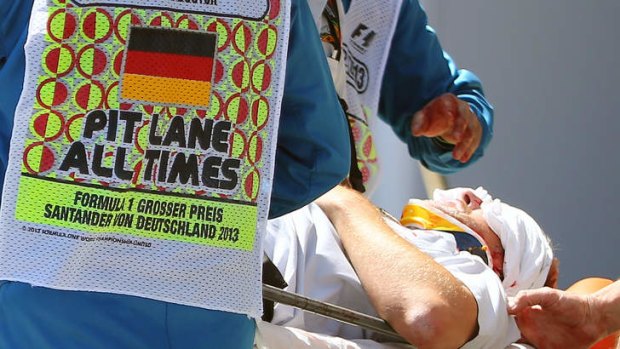 Medics and F1 team members assist Paul Allen, a cameraman injured after the tyre hit him in the back.