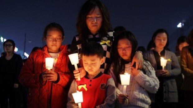 Students hold candles as they pray for the safe return of missing passengers who were travelling aboard south Korean ferry the Sewol. The death toll has climbed to 150.