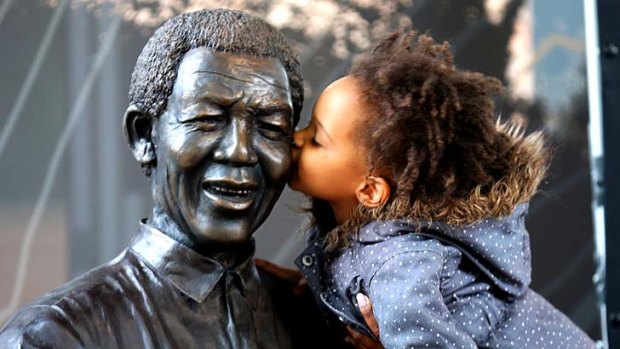 A young South African girl kisses a statue of the late South African president Nelson Mandela.