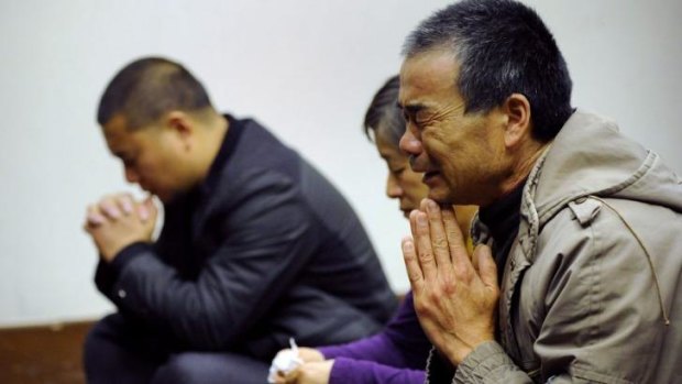 Relatives of passengers from the flight pray before a meeting in Beijing in March.