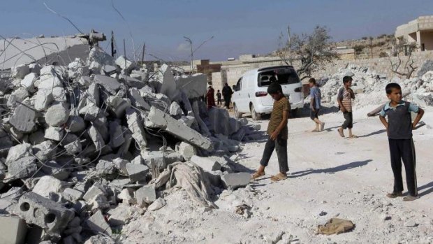 Residents inspect damaged buildings in what activists say was a US strike, in Kfredrian, Idlib province.