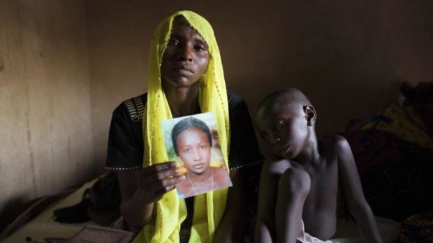 Rachel Daniel, 35, holds up a picture of her abducted daughter Rose Daniel, 17, as her son Bukar, 7, sits beside her at her home in Maiduguri, Nigeria.