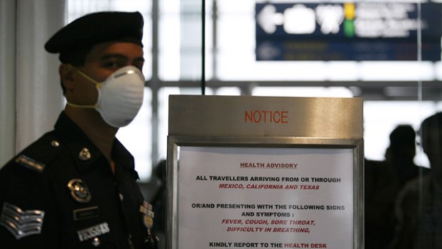 Airport screenings ... A policeman stands next to a health advisory before the arrival of a flight from Los Angeles via Taipei, to screen passengers for possible swine flu infection, at Kuala Lumpur International Airport.
