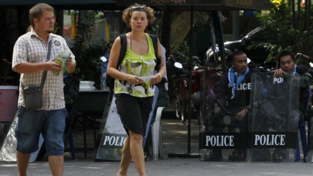 Walk this way: Tourists walk past riot policemen at Dusit Zoo in Bangkok in late November. The tensions continue.