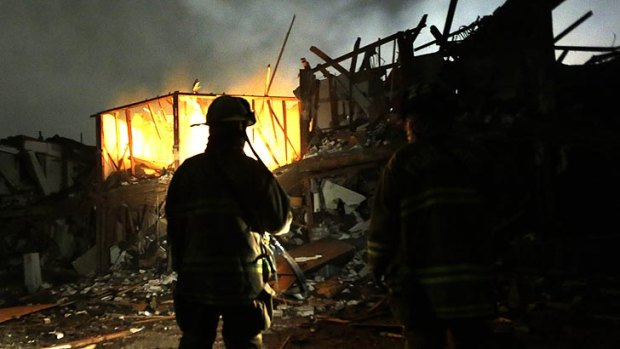 Firefighters use torches to search a destroyed apartment complex near the West fertiliser plant.