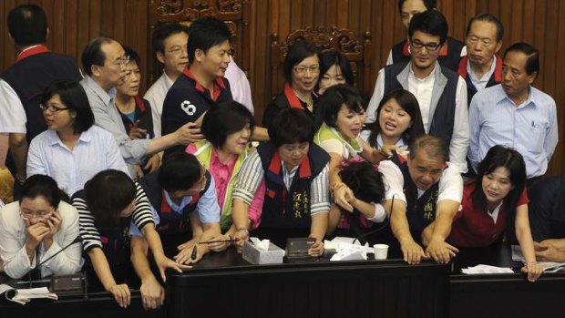 Taiwanese MPs scuffle during a debate over capital gains tax.