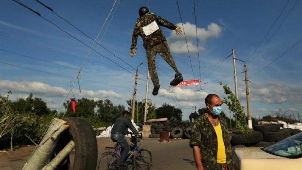 An effigy of a Ukrainian soldier hangs above pro-Russian rebel Oleg Gerasimov standing guard at a checkpoint on the outskirts of Slaviansk.