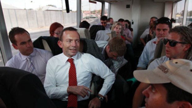 Slumming it with journalists, photographers and camera operators ... Tony Abbott takes a turn on the media's bus in Brisbane.