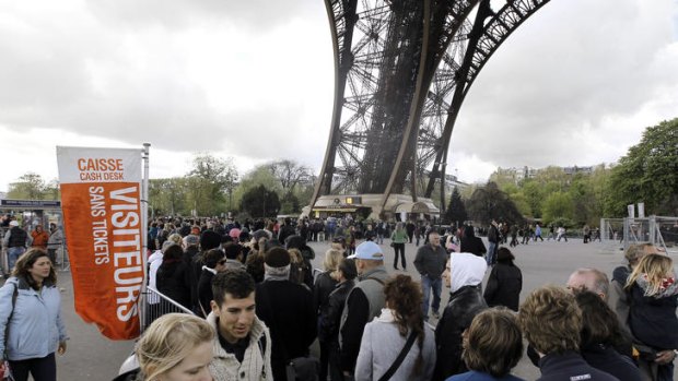 Visitors queue up in front of the Eiffel Tower.