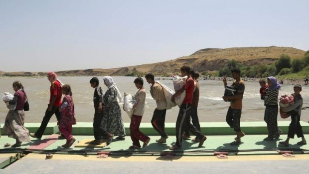Yazidis fleeing ISIL militants cross the bridge spanning the Tigris river on the Iraqi-Syrian border.