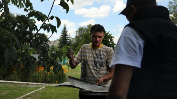 Alexey Vladimirovic brings a piece of  plane debris and a silver necklace from flight MH17 to the OSCE team.