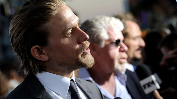 Charlie Hunnam faces the press at the premiere of <i>Sons of Anarchy</i> Season 6 in Hollywood, California.  Co-stars Ron Perlman and Kim Coates in the background.