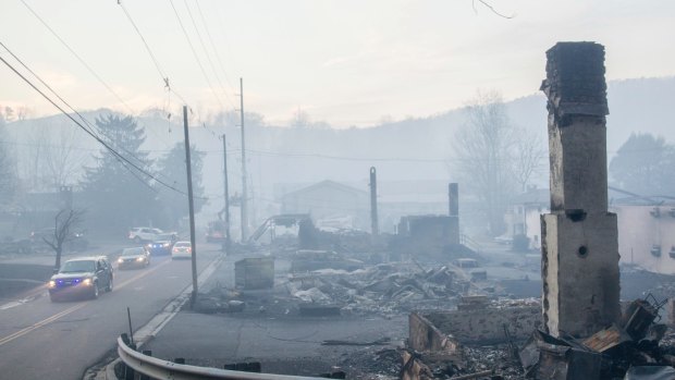 Law enforcement vehicles drive through the smoke near structures destroyed by wildfires in Gatlinburg, Tennessee. 