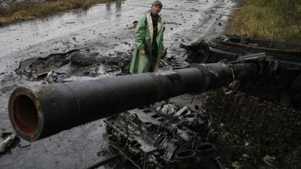 A Ukrainian soldier near a destroyed tank of pro-Russian separatists near Slaviansk