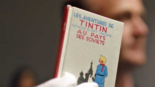 A porter displays a book by Herge at the auction of rare Tintin memorabilia.