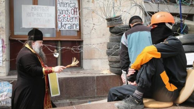 An Orthodox priest blesses a pro-Russian activist as he stands outside the occupied regional administration building in the eastern city of Donetsk.