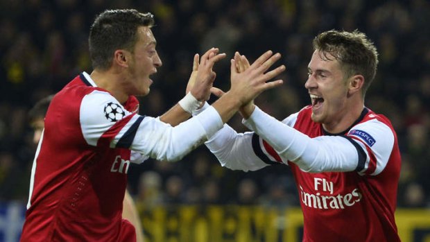 Fire away: Arsenal midfielders Mesut Ozil (left) and Aaron Ramsey celebrate after Ramsey's winning goal against Borussia Dortmund during the week.