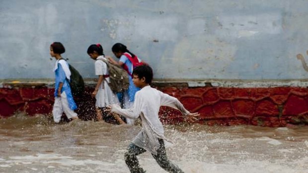 Water world ... children return home from school as a boy darts down a waterlogged road in Delhi. The rain has heightened concerns about the city's readiness for the Commonwealth Games.