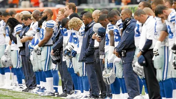 Sombre mood ... Dallas Cowboys players hang their heads during a moment of silence honouring teammate Jerry Brown.