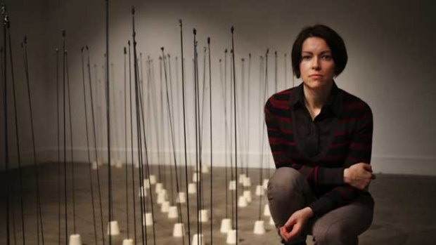 Dorota Mytych and her installation. At the top of each rod is a clay sculpture of a human.