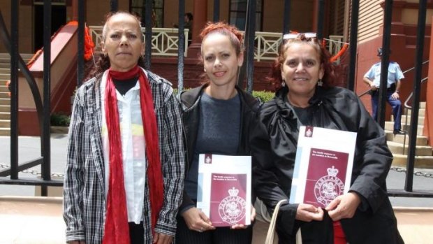 Family members of Evelyn Greenup-Davis outside the gates of Parliament holding the report findings.