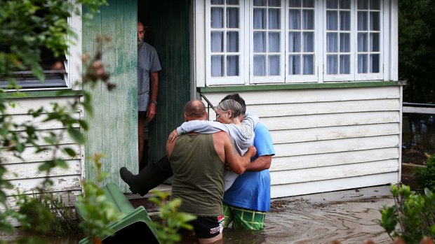 Long time local resident Carol is assisted from her home by neighbours as flood waters rose in Kokoda Street on April 1 at Beenleigh.