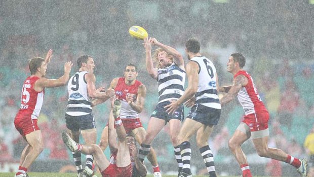 Sydney and Geelong players tussle for the ball in wet and windy conditions at the SCG.