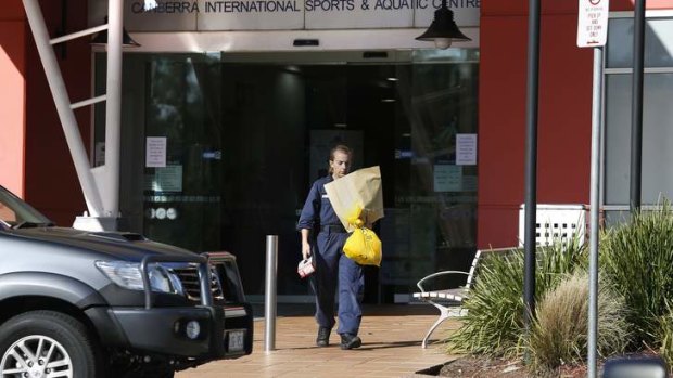 A forensic investigator carries items from the Canberra International Sports and Aquatics Centre in Belconnen after the incident.