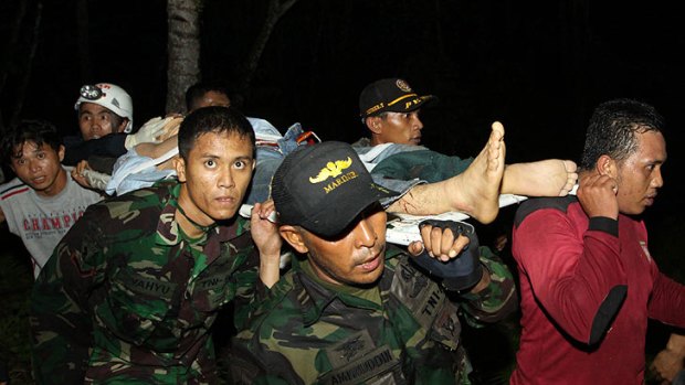 Rescuers carry a survivor from the wreckage of a helicopter carrying Australian mine workers in Bitung, North Sulawesi.