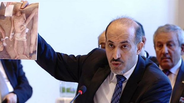 Syrian opposition leader Ahmad al-Jarba holds up recently released pictures that purport to show deaths in Syrian regime custody at the talks in Montreux on Wednesday.