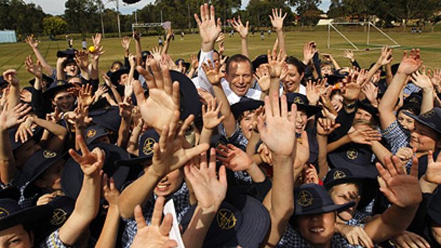 Contrast ... Opposition Leader Tony Abbott is mobbed by students at a school in Bowman last month. Labor is accused of not putting enough effort into the ultra-marginal seat.