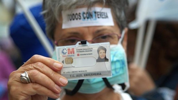 A protester holds her nurse's ID card in Madrid. The slogan on her head is Spanish for "all of us are with Teresa".