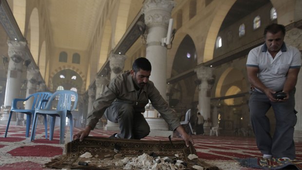 Palestinians clean up debris inside the al-Aqsa mosque on Wednesday following clashes between stone-throwing Palestinians and Israeli securitry forces.