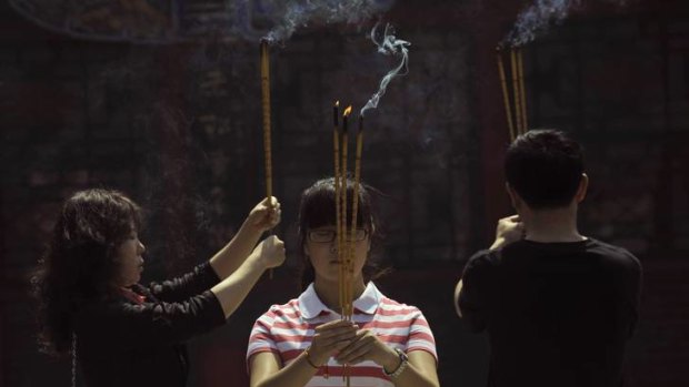 Praying for success ... a family holds burning incense as they pray for the daughter's success in the upcoming National College Entrance Exam at a Taoist temple in Shenyang, Liaoning province.