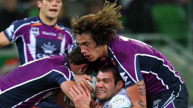 Tim Grant of the Panthers is tackled by Melbourne Storm players.