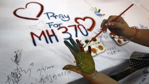 Hopeful ... A woman paints her palm with water colors during an event for passengers aboard a missing Malaysia Airlines plane, in Kuala Lumpur, Malaysia.
