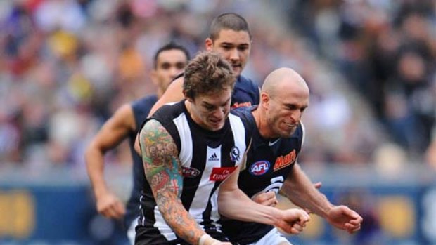 Blues skipper Chris Judd receives a heavy hip and shoulder from Magpie onballer Dayne Beams yesterday.